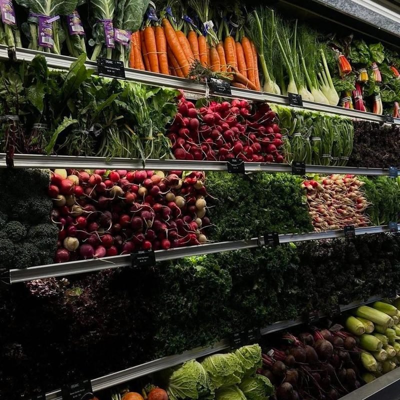 Bancada de hortifrúti com verduras, cenouras, rabanetes e beterrabas