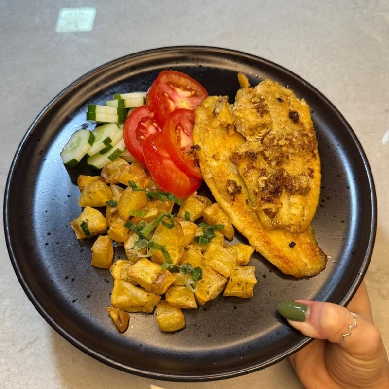 Prato com peixe grelhado, batatas assadas, tomate e pepino